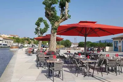 a group of tables and chairs with red umbrellas at Chez Gaëlle in Trèbes