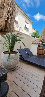 a wooden deck with a potted plant and a bench at L'oiseau du paradis in Narbonne