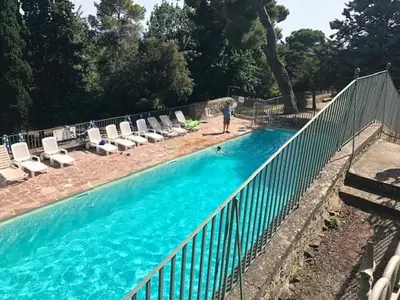 a person standing next to a fence next to a swimming pool at château de Paulignan in Trausse
