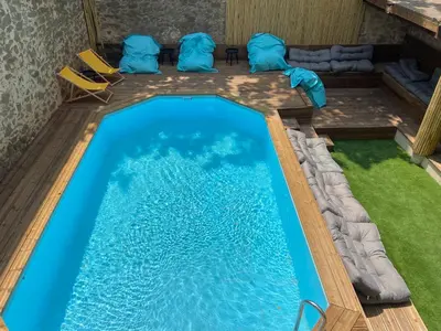 a swimming pool in a house with blue water and chairs at T2 bord du canal du midi piscine in Homps