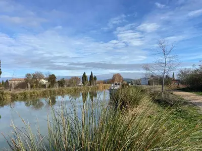 a body of water with trees and buildings in the background at T2 bord du canal du midi piscine in Homps
