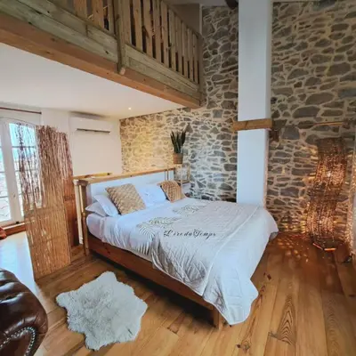 a bedroom with a bed and a stone wall at La Maison du Canal- vue Canal- L'ère du Temps in Homps