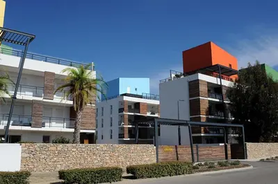 a building with a palm tree in front of it at Location saisonnière Résidence Ephyra Gruissan in Gruissan
