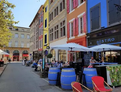 a street with tables and chairs and umbrellas on a city street at La maison de Camille climatisation parking privé WIFI in Carcassonne