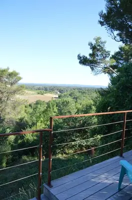 a wooden deck with a bench and a view of trees at Chalet, calme, absolu, superbe vue, et piscine (en été) in Ventenac-Cabardès