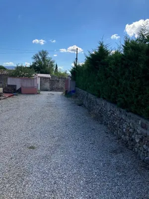 a gravel road next to a stone wall at Chambre d'hôte Les maisons de Gaia in Tuchan