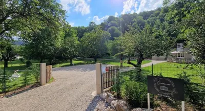 a gate in a park with a house in the background at Lodge tente les pommiers Glamping Ô rendez-vous en demi-pension in Roquefeuil