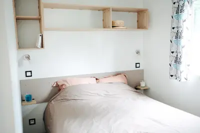 a small bedroom with a bed with white sheets at Mobil Home XXL 4 chambres - Camping Tarn - Domaine du Koukano in Maurens-Scopont