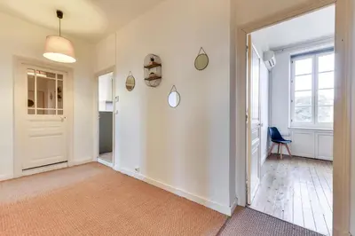 a hallway with white walls and a door and a chair at El Marty - central - climatisation - parking gratuit - wifi in Carcassonne
