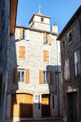 an old stone building with wooden doors and a tower at Suite Présidentielle Maison de L'Église in Narbonne