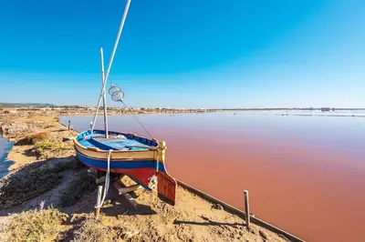 a boat sitting on the shore of a body of water at Vagues et Vignes Gruissan Appt T2 bien placé tout équipé WIFI avec parking privé in Gruissan