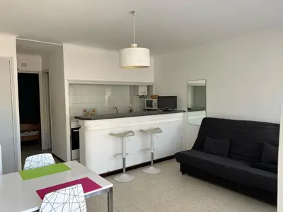 a living room with a couch and a kitchen at Agréable T2 pour 5 pers, 1er étage, climatisé, parking sécurisé - FR-1-797-6 in Port-la-Nouvelle