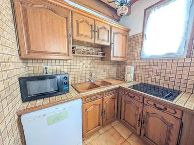 a kitchen with wooden cabinets and a sink and a microwave at T3 duplex 50m², 2 chambres, proche plage, 6 pers - FR-1-797-1 in Port-la-Nouvelle