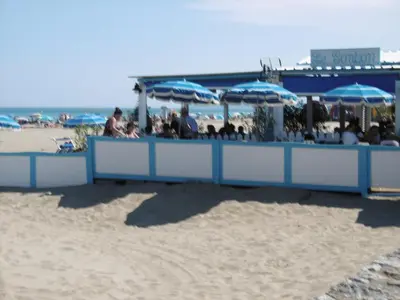 a group of people sitting under umbrellas on the beach at Charmant T3 rénové à 60m de la plage avec terrasse, jardin et parking clos - FR-1-797-28 in Port-la-Nouvelle