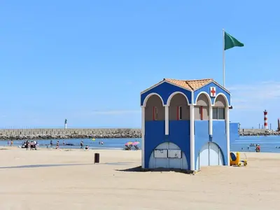 a person walking down a sidewalk next to the beach at Port-la-Nouvelle : Studio front de mer, 4 pers, parking inclus - FR-1-797-32 in Port-la-Nouvelle