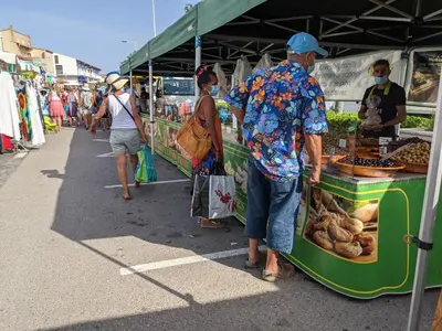 a man standing in front of a food stand at a market at Villa T3 climatisée, 57m², 5/6 pers, proche plage, rénovée, terrasse, parking, quartier animé - FR-1-797-48 in Port-la-Nouvelle
