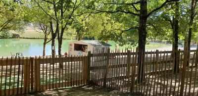 a fence with a house in the middle of a lake at Le Loft in Caraman