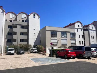 a parking lot with cars parked in front of a building at L'appart B42 in Gruissan