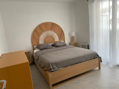 a bedroom with a large bed with a wooden headboard at Très beau F2 neuf 50 M2 , grande terrasse 30 M2, très bien situé in Narbonne