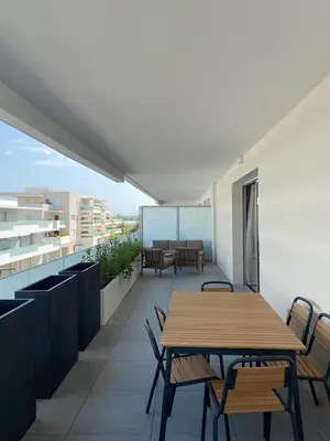 a balcony with a wooden table and chairs at Très beau F2 neuf 50 M2 , grande terrasse 30 M2, très bien situé in Narbonne