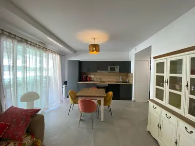 a kitchen and living room with a table and chairs at TRES BEL F2 NEUF, GRANDE TERRASSE, TRES BIEn SITUE in Narbonne