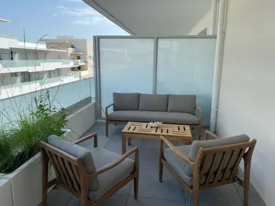 a balcony with a couch and two chairs and a table at TRES BEL F2 NEUF, GRANDE TERRASSE, TRES BIEn SITUE in Narbonne
