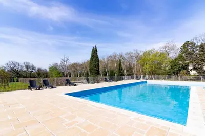 a swimming pool with blue water in a yard at Le Clos d'Azille - Appt pour 6 personnes in Azille