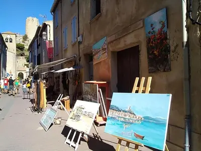 a street with paintings and easels on the side of a building at T2 Spacieux, Proche Plage, Parking Privé - FR-1-796-82 in Gruissan