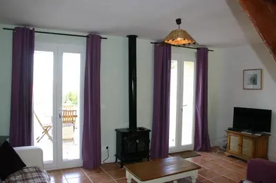 a living room with purple curtains and a wood stove at Fossat in Villautou