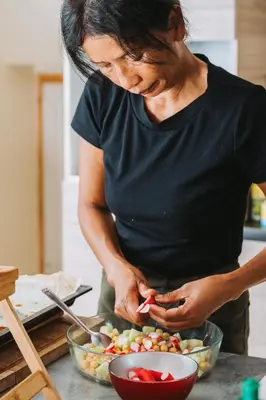 a woman standing in a kitchen preparing food at Ecolodge - Calme - Piscine privée - vue nature in Roquetaillade