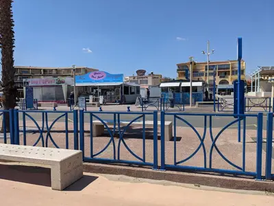 a blue fence with a bench in a parking lot at Maison T4 110m² avec jardin clos, à 1500m de la plage - FR-1-797-60 in Port-la-Nouvelle