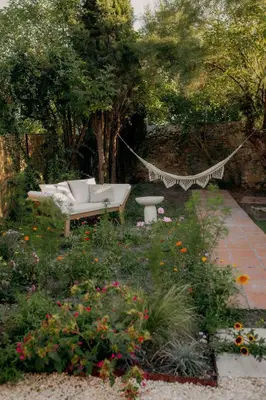a hammock in a garden with a bench and flowers at Cozy And Refined Retreat In The Heart Of Fanjeaux in Fanjeaux