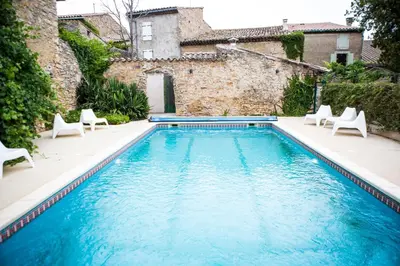 a swimming pool with chairs and a building at O'MAZETTE CHAMBRE ROMANTIQUE VUE JARDIN AVEC PISCINE découverte de l'Aude in Fabrezan