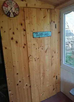 a wall of a log cabin with a clock on it at La Succulente Vivace in Cambounès