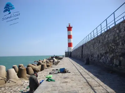 a man standing on the beach with a lighthouse at Bleu Riviera Lumière, Calme et Air Marin in Port-la-Nouvelle