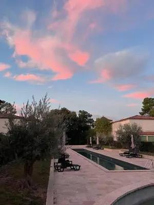 a swimming pool with benches and a cloudy sky at La Redorte Appartement au château 8 in La Redorte