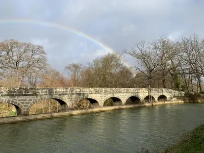 a rainbow over a stone bridge over a river at La Redorte Appartement au château 8 in La Redorte