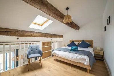 a bedroom with a bed and a blue chair at Le Chenal - Appartement Duplex proche des halles in Narbonne