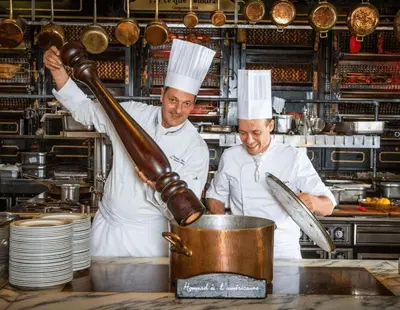 two chefs in a kitchen preparing food in a pot at L'Alcazar - Appartement à deux pas des halles - Climatisation in Narbonne