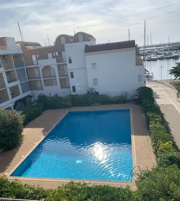 a large blue swimming pool in front of a building at Bel appartement avec piscine et vue bateaux in Gruissan