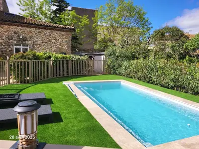 a bed in a room with a couch and a tv at Gîte Coté Village - le cœur du village avec piscine in Salles-d'Aude
