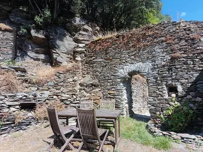 two chairs and a wooden table in front of a stone wall at Chambre b&b in Miraval-Cabardès