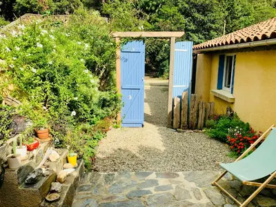 a blue door leading into a yard with a chair at Peaceful Gite By The Black Mountain in Caunes-Minervois