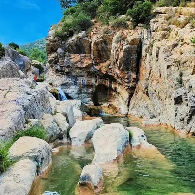 a river with rocks and waterfalls on a mountain at Hebergement privatif coeur de village in Maury