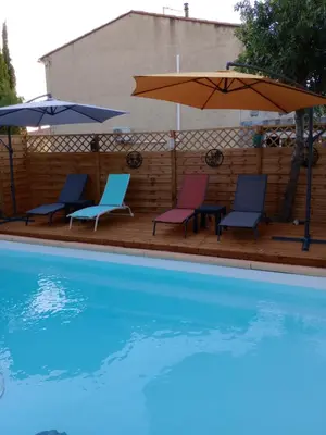 a group of chairs and umbrellas next to a pool at chambre et table d'hôte au coin de la cité in Carcassonne