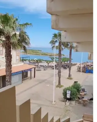 a table and chairs with a red umbrella on a balcony at Le Thalassa I in Gruissan