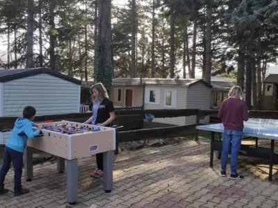 a woman and two children playing with a table football at Mobil-home confortable avec terrasse pour 4 personnes à Sournia - API-1-52-622 in Sournia