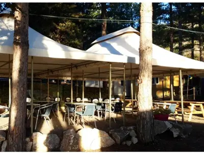 a patio with tables and chairs under a white umbrella at Mobil home confortable avec terrasse à Sournia - API-1-52-319 in Sournia