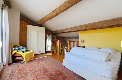 a bedroom with a white bed and a yellow wall at La Maison Bleue de Sigean - Loft 2 in Sigean