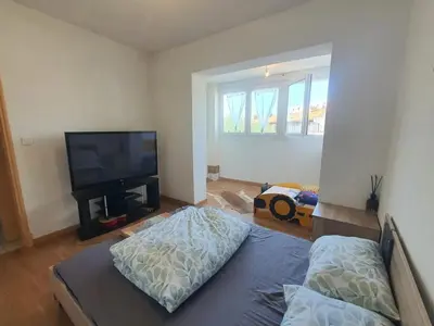 a living room with a flat screen tv and a bed at Maison confortable à Carcassonne avec jardin privé in Carcassonne